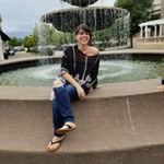 Savannah is sitting on the edge of a water fountain, smiling