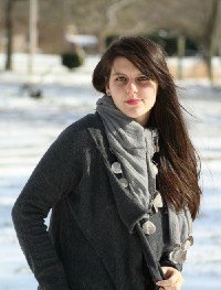 Savannah is smiling, wrapped up in dark grey coat, a light grey scarf in snowy weather