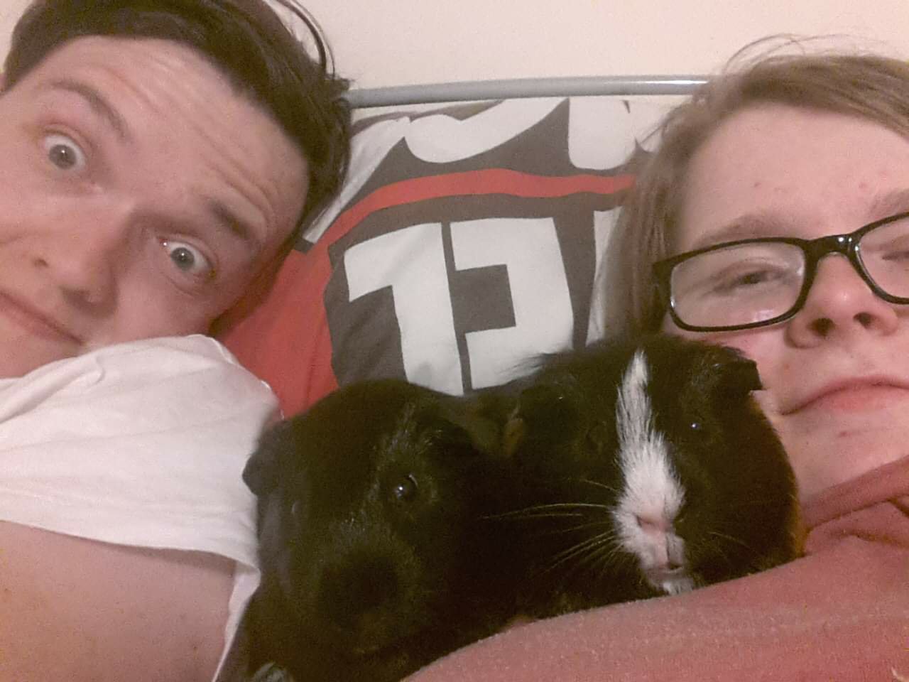 Ewan and Ami on their bed, cuddled up with Thor and Loki in-between them