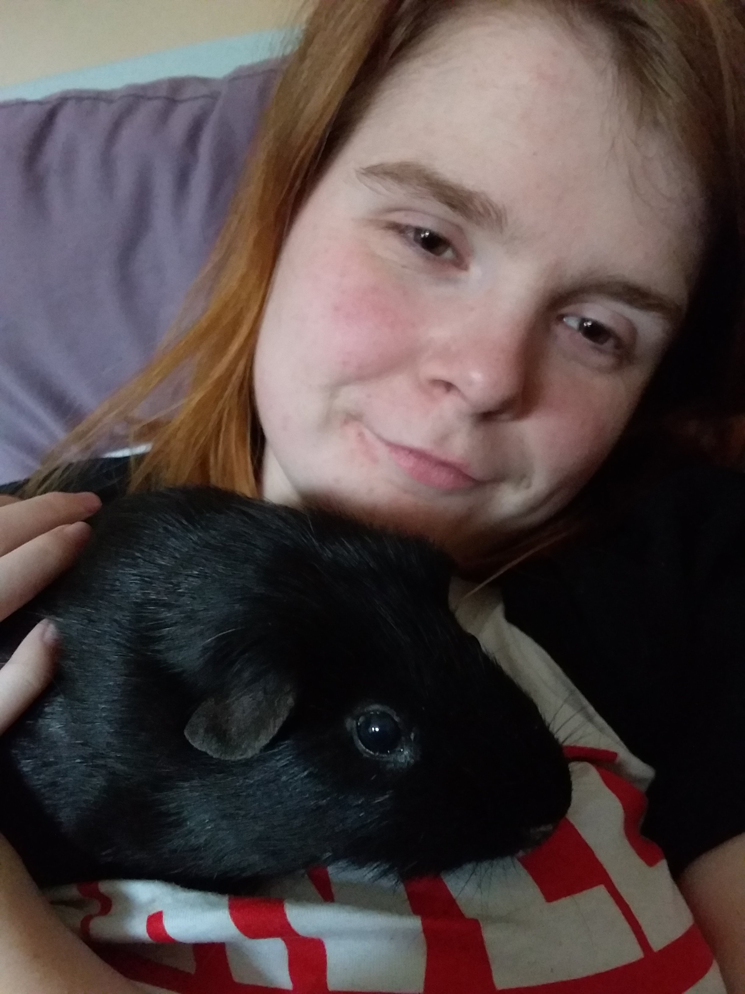 Ami is in bed, smiling, with Thor resting on her