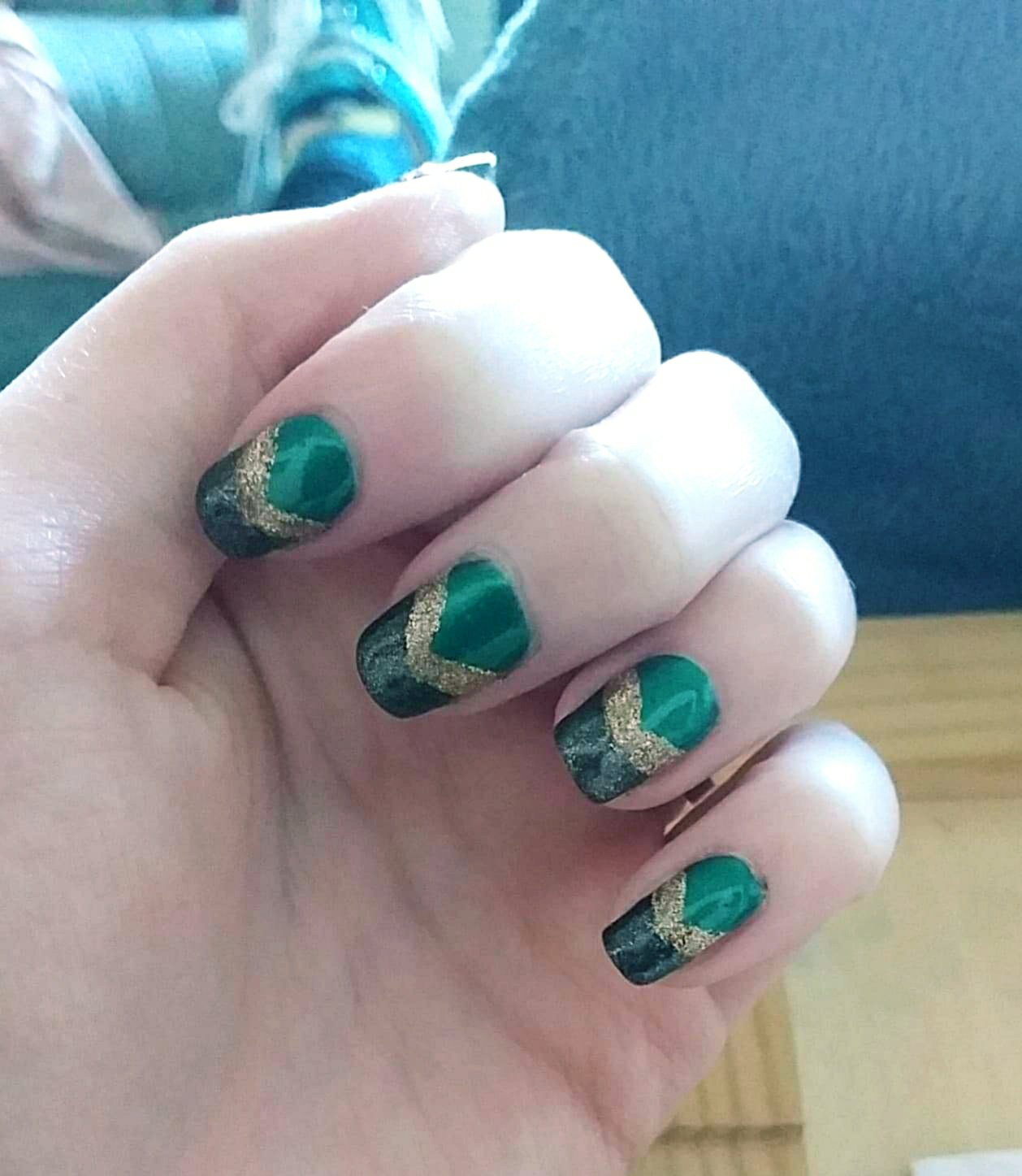 Description of Ami's nail design: the base is dark green, with sparkly black tips, and sparkly gold arrow heads in between the green and black