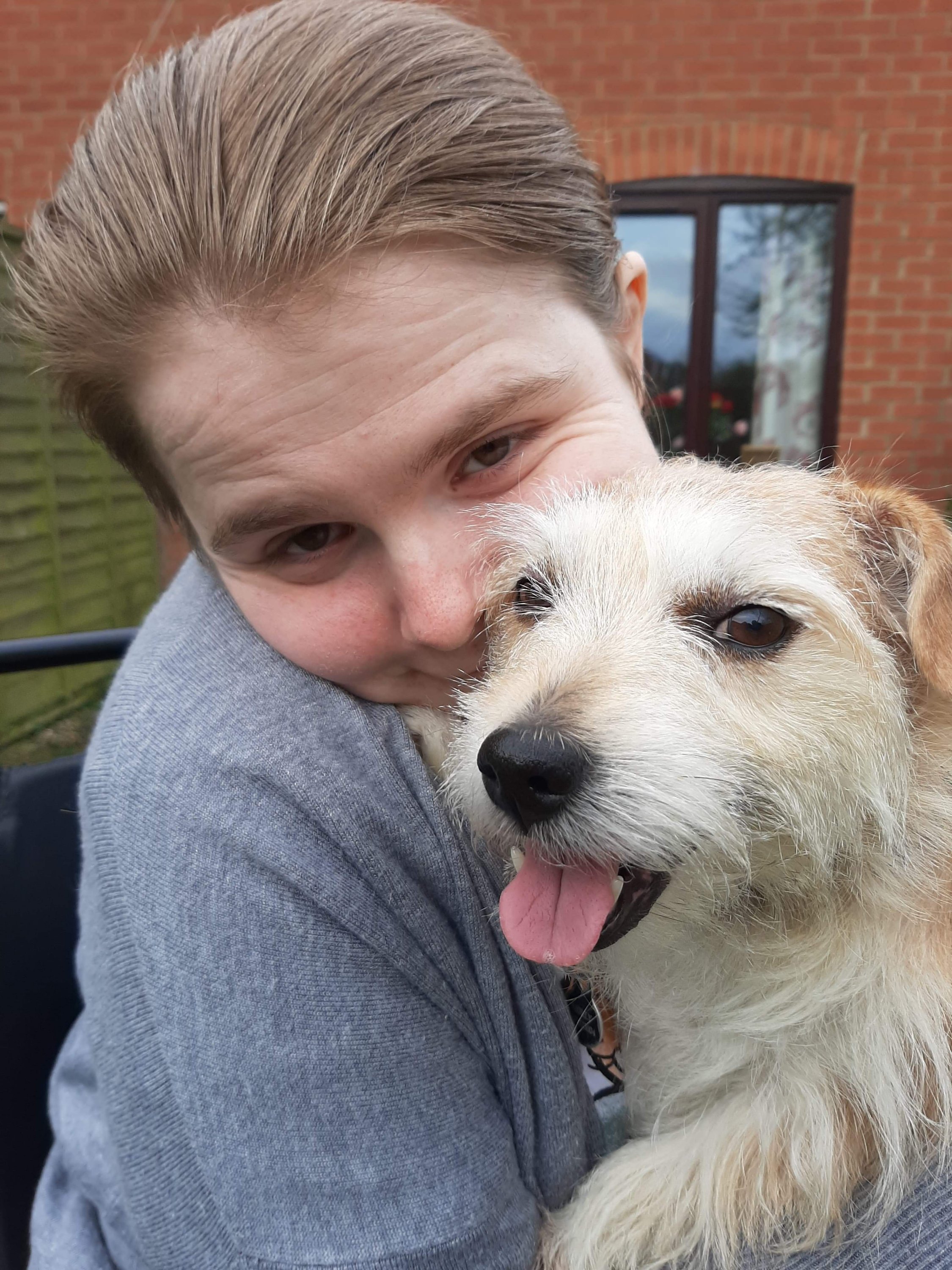 A close up of Ami, in her powered wheelchair, with Molly cuddling close.