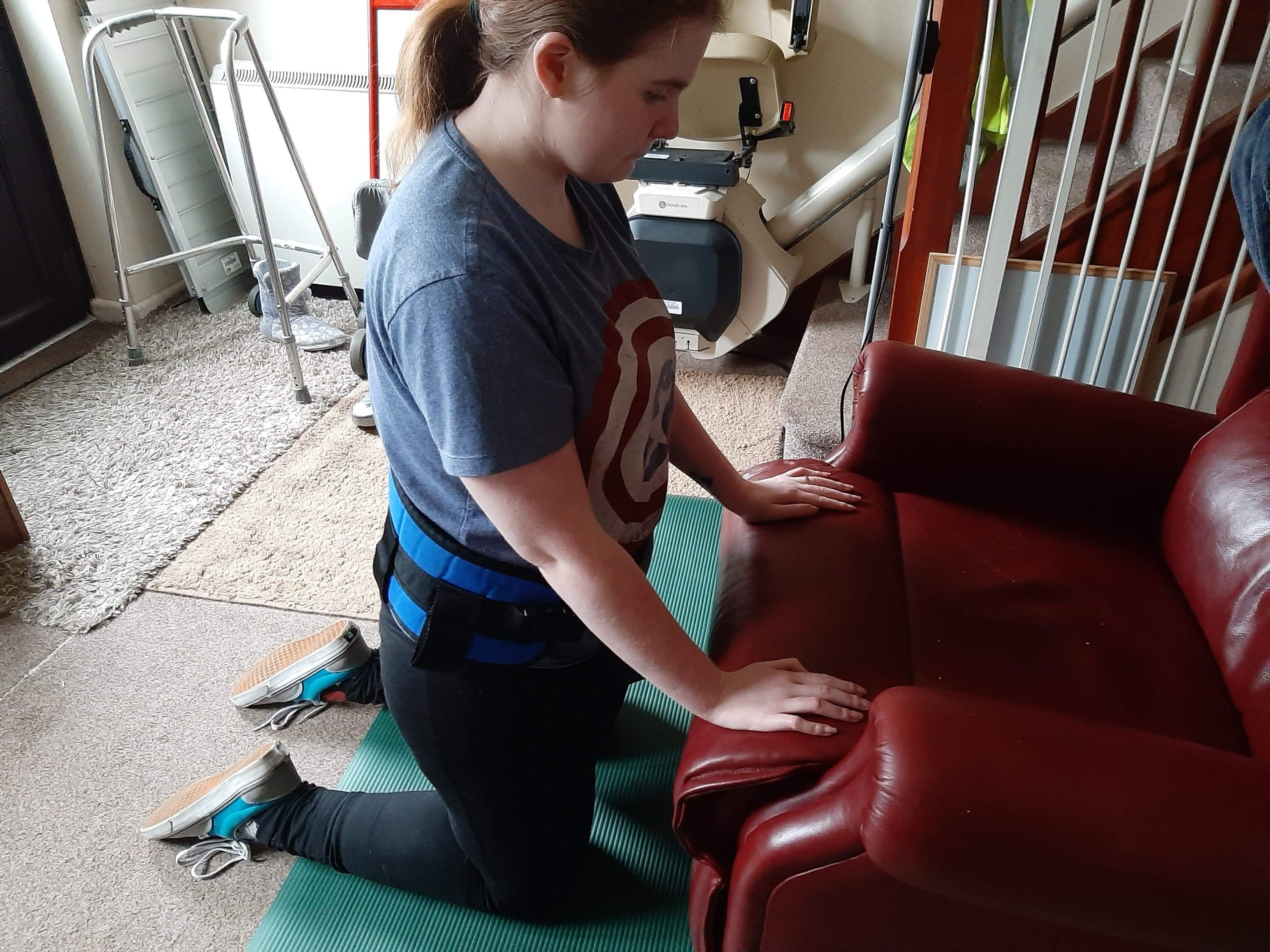 Ami is kneeling on a green yoga/physio mat which is helping her in doing physio at home