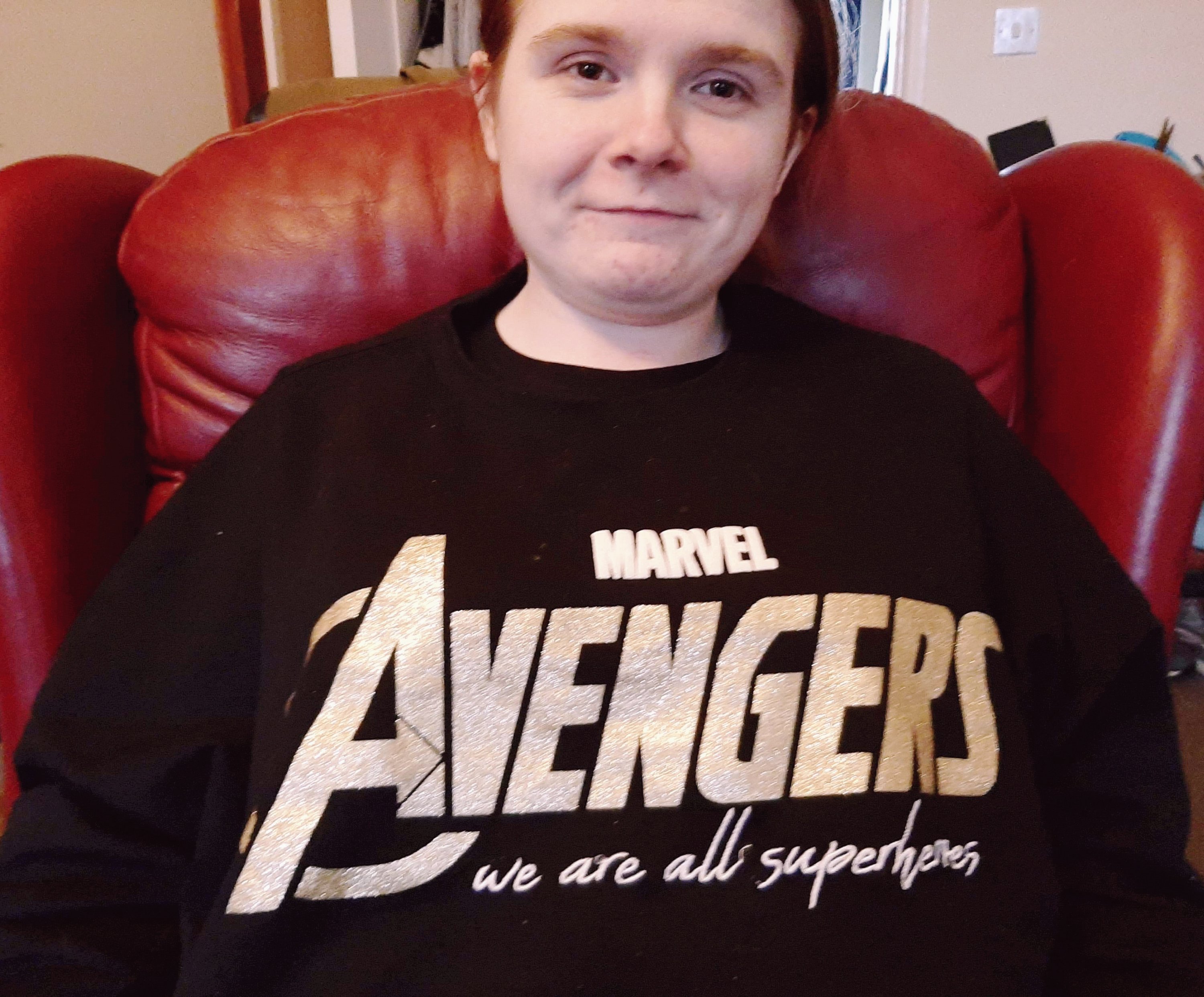 Ami is wearing a black jumper with the Avengers logo in glittery gold, and has the phrase 'we are all superheroes' underneath.