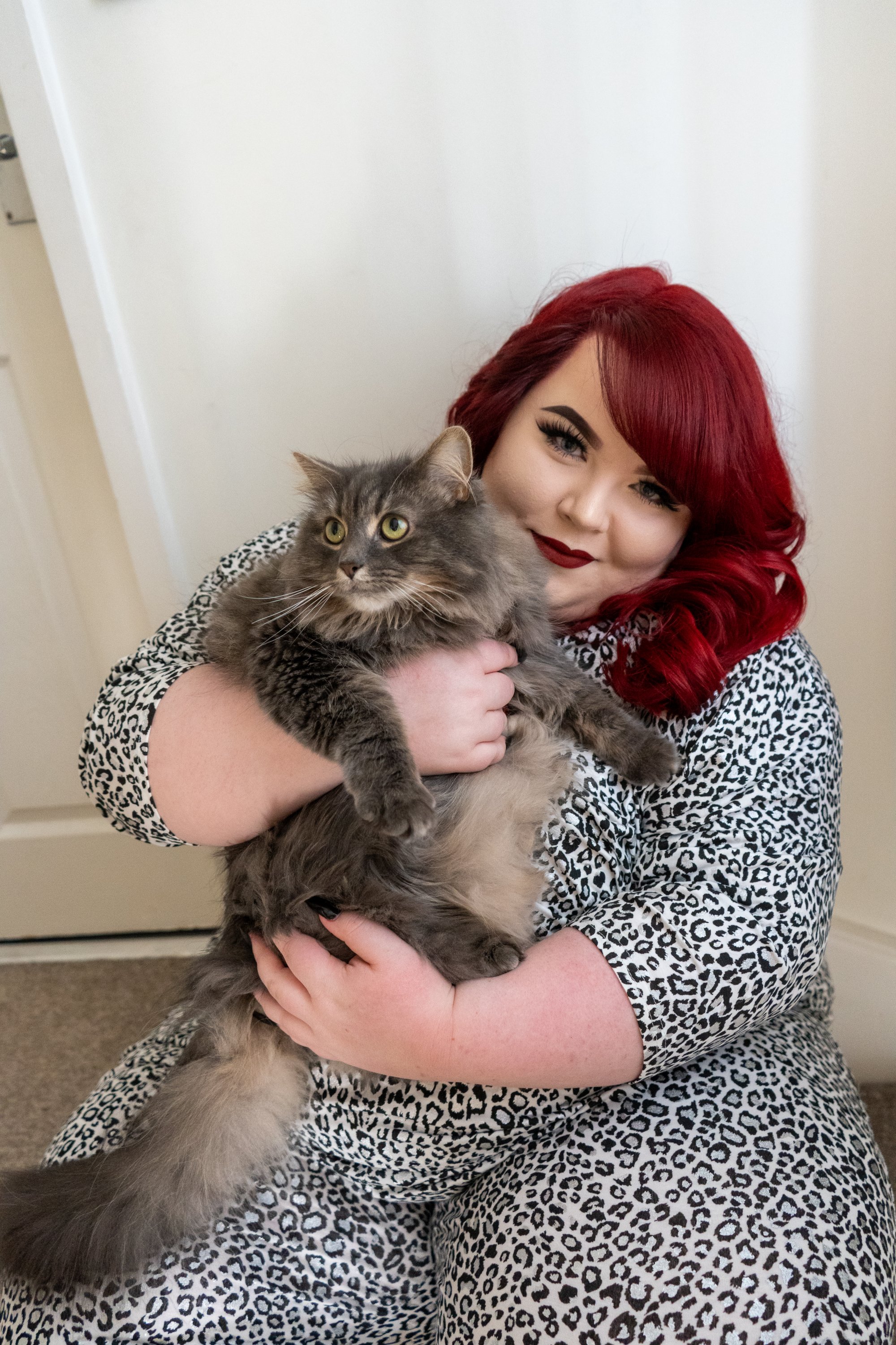 Photo of Georgina sitting, cuddling Bella, her adorable big fluffy grey cat.