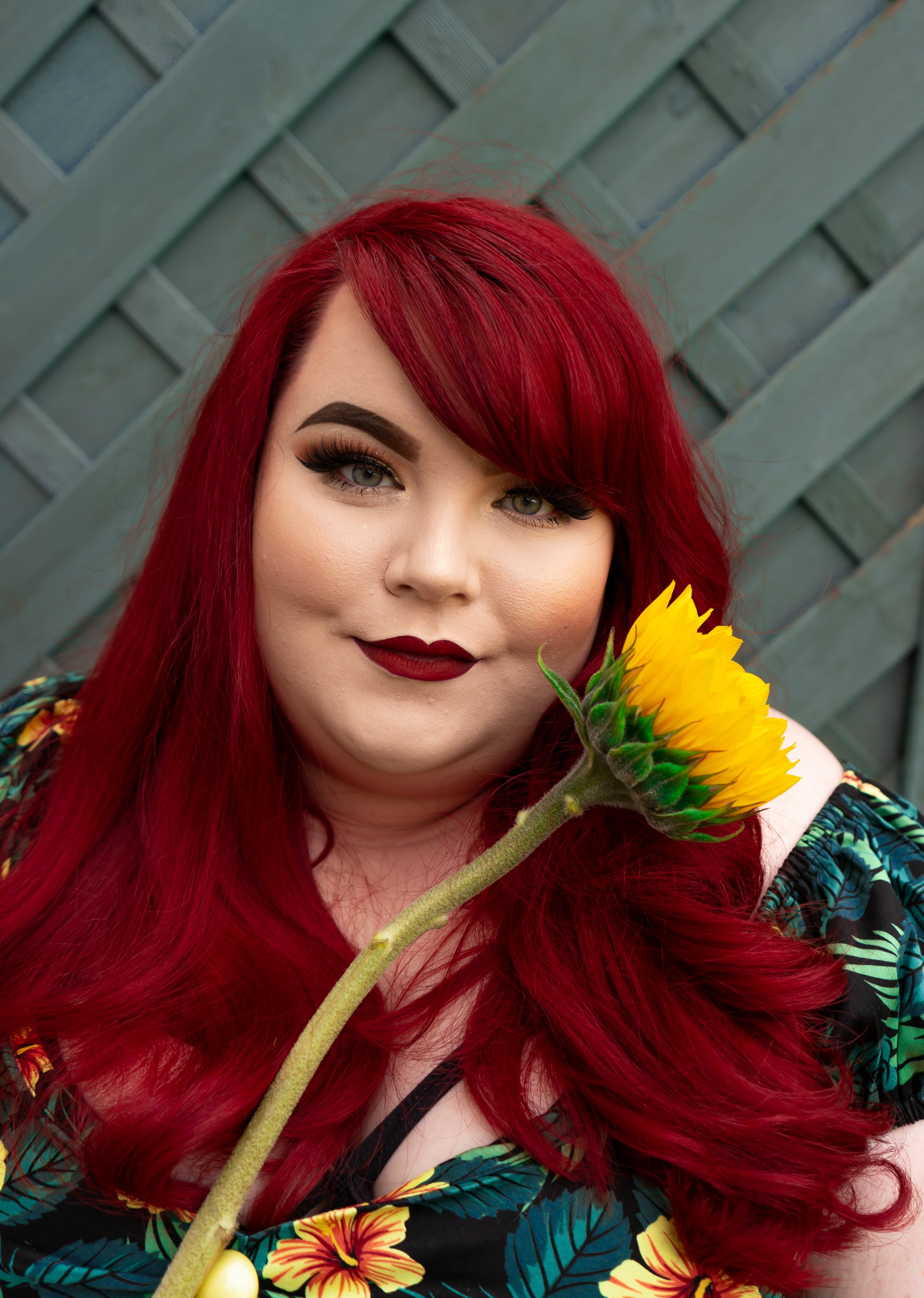 Photo of Georgina, smiling at the camera, and holding a single sunflower