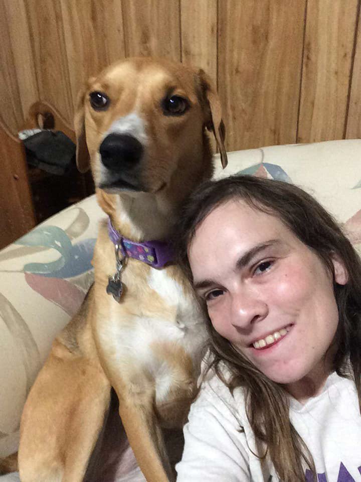 Jamie is smiling at the camera, with her dog Beignet, an American Foxhound