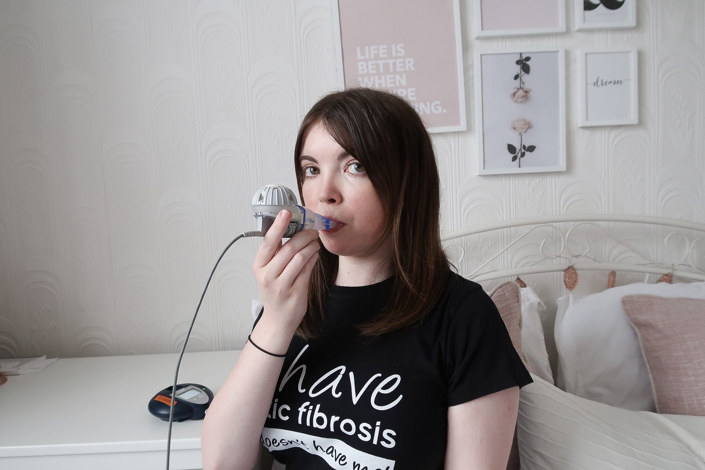 Lucy is looking at the camera, using her inhaler.