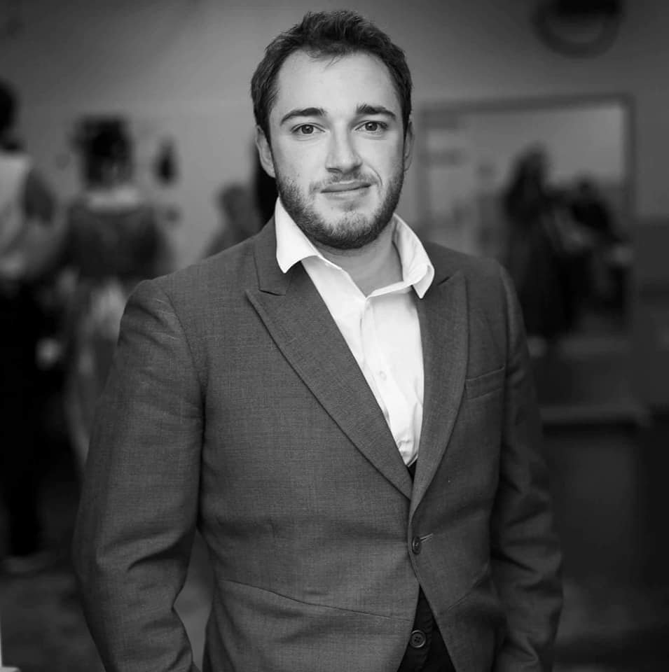 Photo of David, wearing a suit, looking at the camera. The photo has the grey-scale effect.