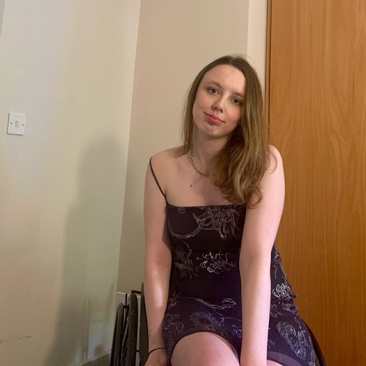 Emily is sitting in her wheelchair, smiling at the camera.