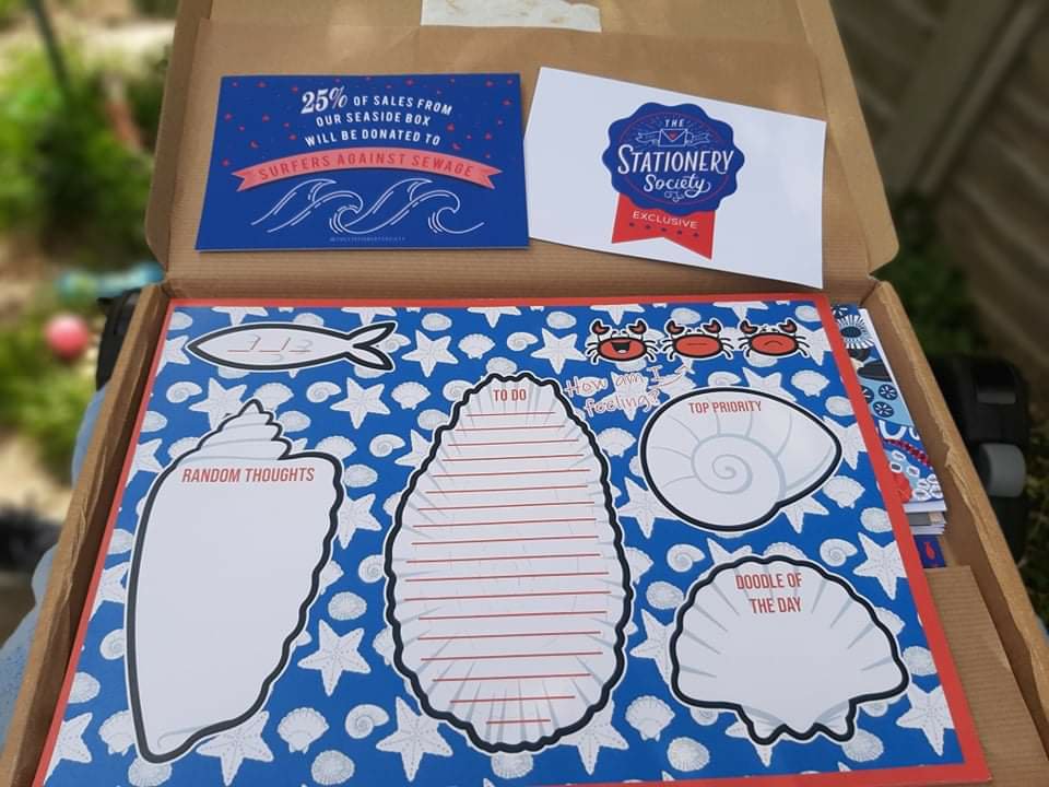 A large notepad with scattered white starfish and seashells against a blue background. There is an outline of a fish to write the date, a trio of crabs representing how you are feeling. On the left side is a big white seashell to write random thoughts in. In the middle is a slightly bigger white seashell as a to-do list. On the right side, below the crabs, are two smaller white seashells, one for writing top priority tasks in, and the other for your doodle of the day.