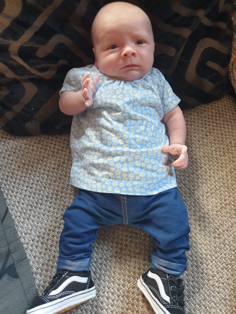 Baby Daisy wearing a light blue top, dark blue jeggings and a pair of black vans