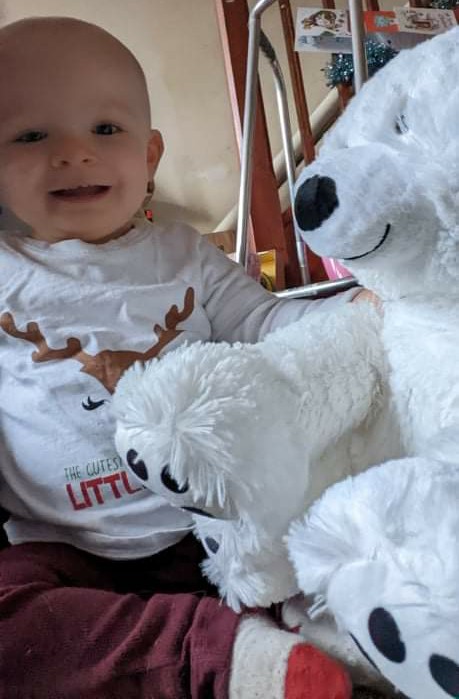 Daisy smiling with a white polar bear soft toy