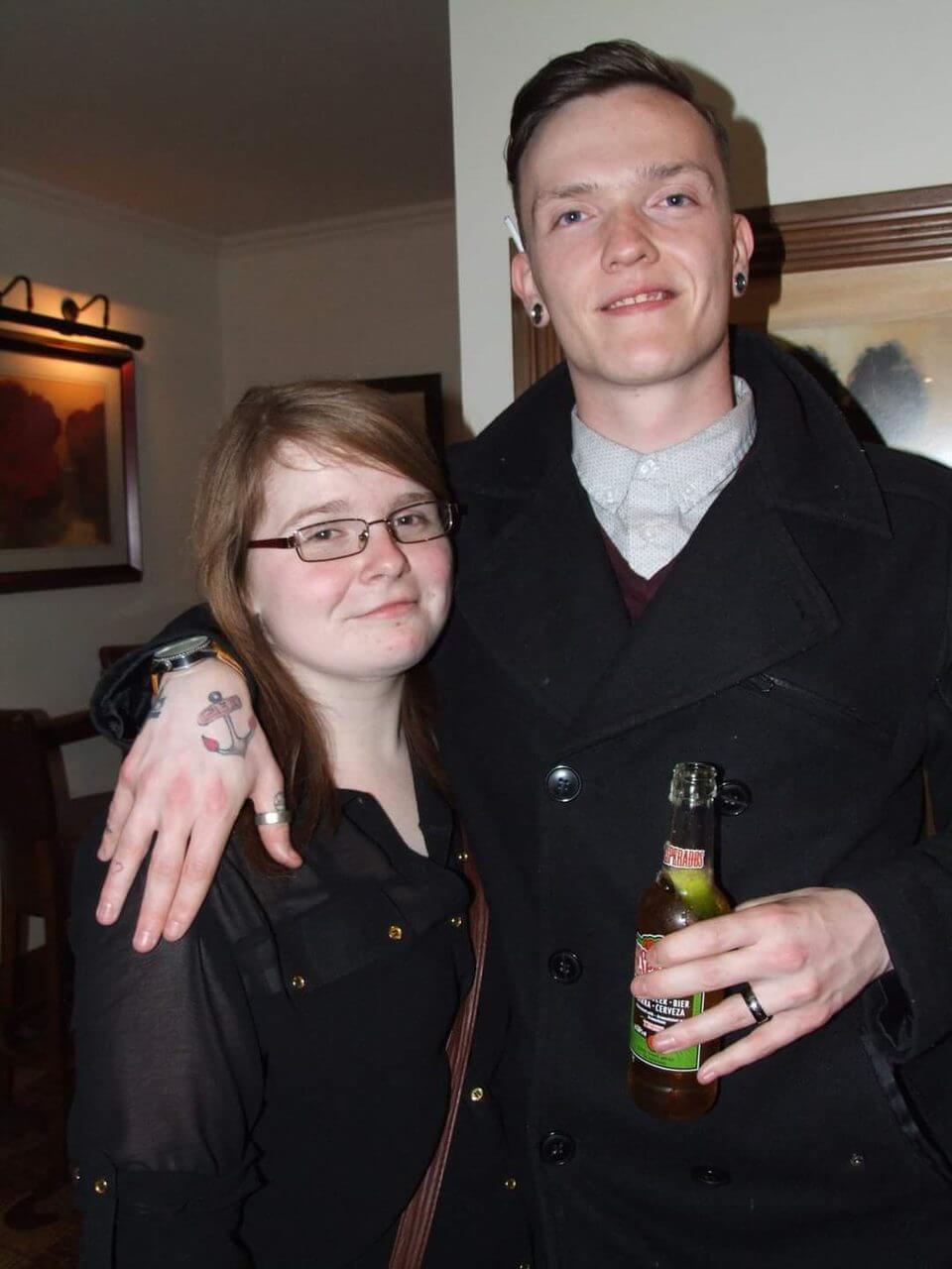 Ami is non-disabled when this photo was taken, she is standing with Ewan, his arm around her shoulders. They are smiling at the camera.
